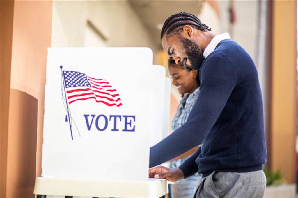 A millennial black man and woman voting at a voting booth in an election.